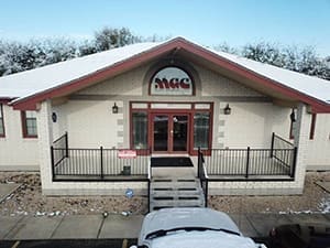 A building with a car parked in front of it, by MGC Contractors.