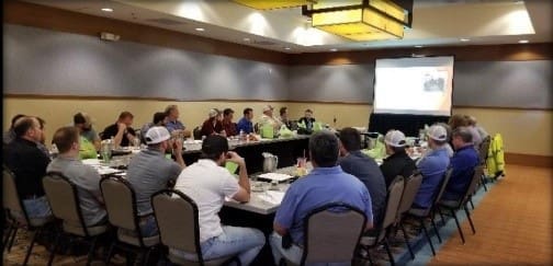A group of people sitting around a table in a conference room, discussing business strategies.