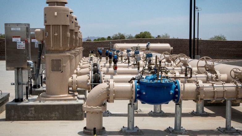 A group of pipes and valves on a concrete slab.